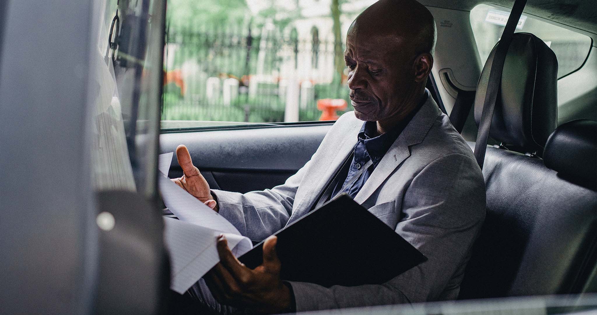 Un responsable qualité assis dans un taxi lisant un compte-rendu 
